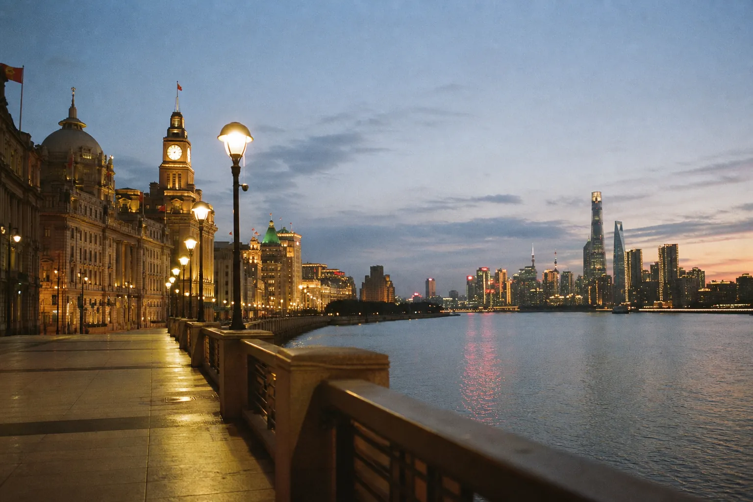 The Shanghai skyline at dusk, historic Bund buildings facing the lit towers of Pudong across the river